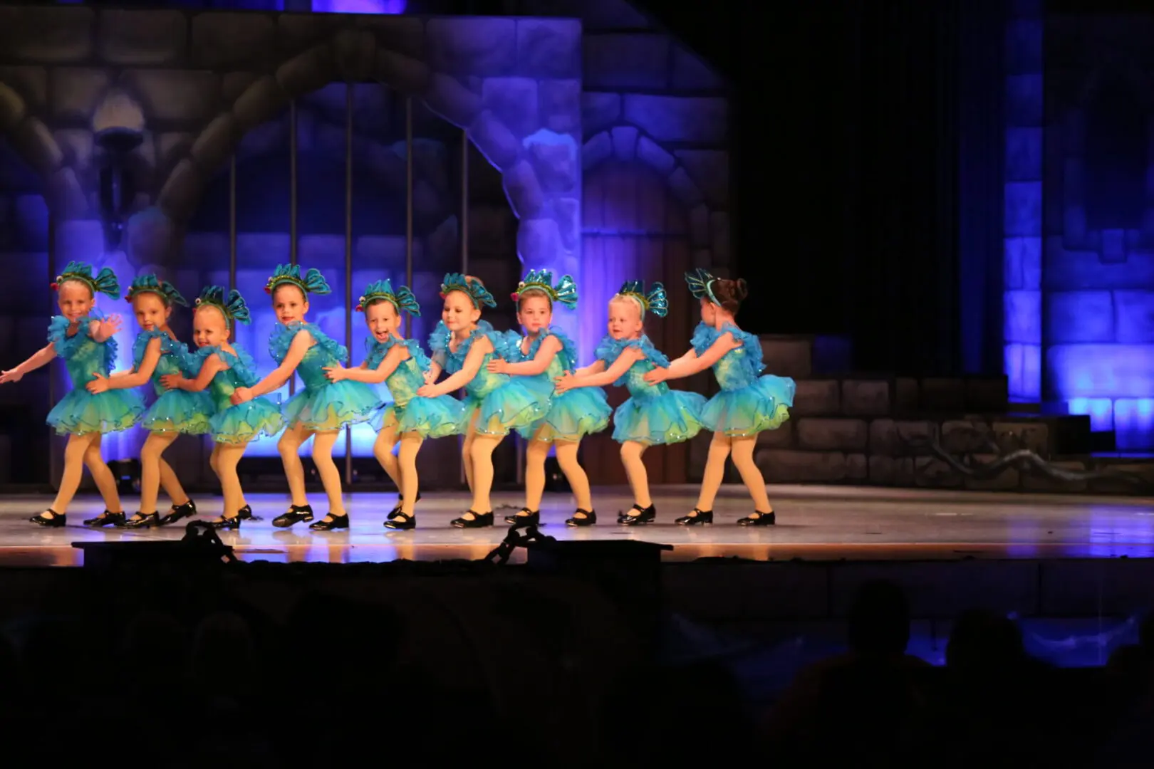 A Group of Girls in Blue and Yellow Costume Dancing on Stage