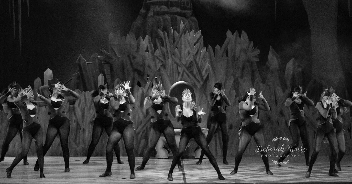A group of women in black leotards and tights performing on stage.