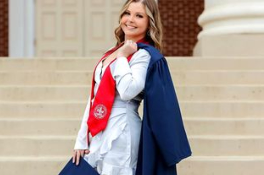 A woman in graduation attire standing on steps.