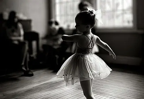 A little girl in a tutu is dancing