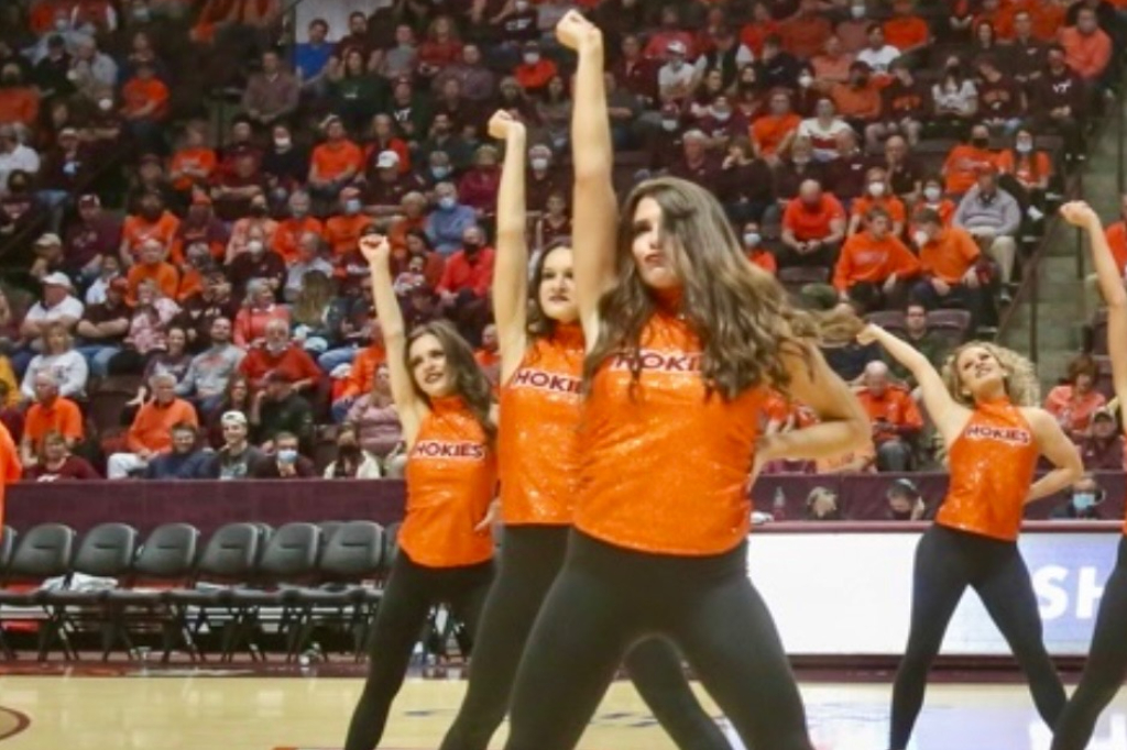 A group of young women in orange shirts performing.