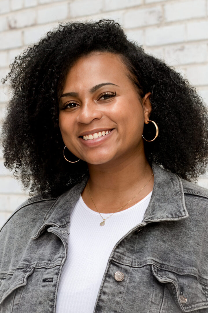 A woman with curly hair wearing a jean jacket.