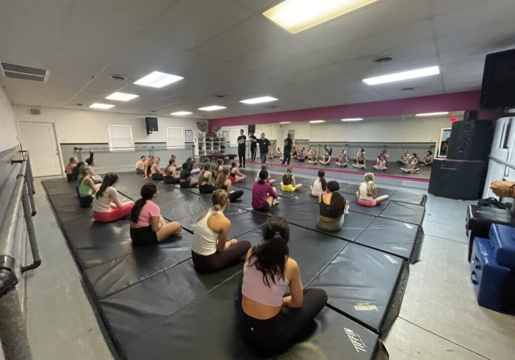A group of people sitting on mats in a gym.
